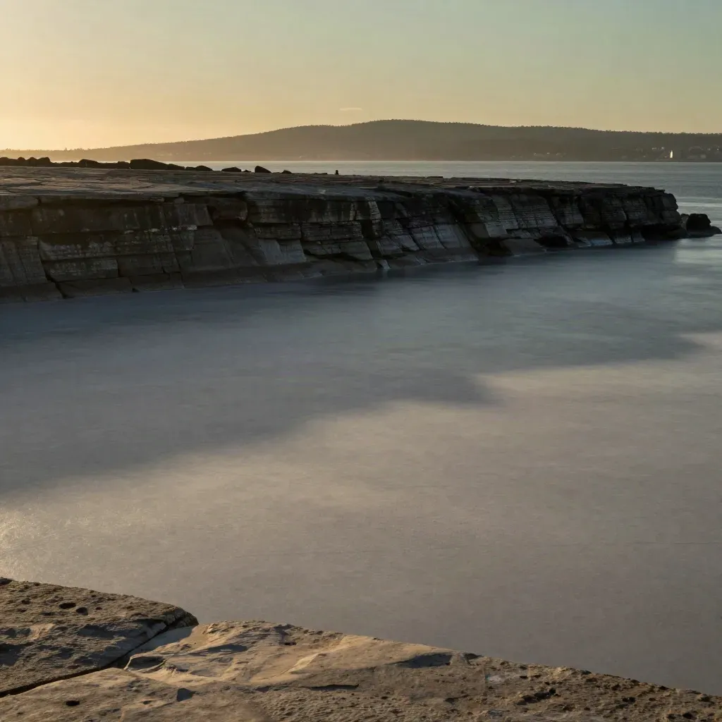 Hazy Hamilton escarpment and harbour with industrial ridge silhouettes at sunset.